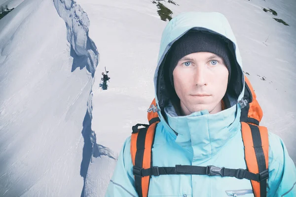 Mladý horolezec na zimní straně hory se dívá do kamery. Přední pohled. Aktivní životní styl v chladném počasí. — Stock fotografie