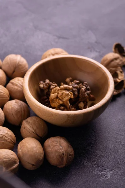 Walnuts in wooden bowl and on blue slate surface. Healthy nuts and seeds composition. — Stock Photo, Image