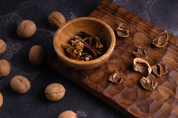 Walnuts in wooden bowl and on blue slate table. Healthy nuts and seeds composition. — Stock Photo, Image