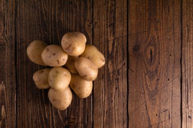 Rustik ahşap yüzeyde taze patates yığını. Organik gıda, karbonhidrat, yumru.
