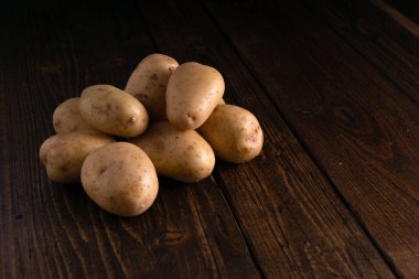 Rustik ahşap yüzeyde taze patates yığını. Organik gıda, karbonhidrat, yumru.