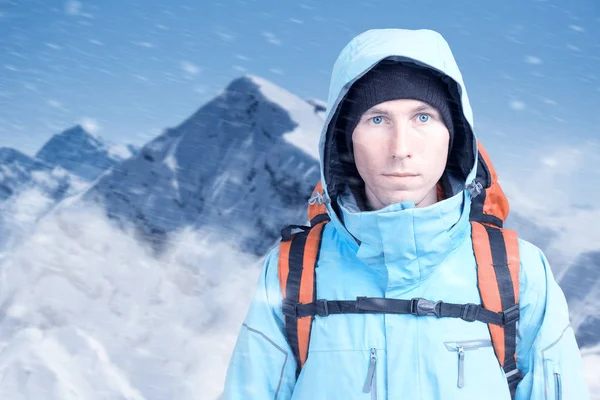 Jovem alpinista do sexo masculino na montanha de inverno vista superior olhando para a câmera. Vista frontal. Estilo de vida ativo em tempo frio. Inverno paisagem de montanha e céu nublado . — Fotografia de Stock
