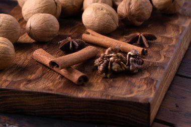 Ceviz, tarçın ve anason ahşap kesme tahtası üzerinde. Masada fındık ve baharatlar var. Gıda bileşimi yakın çekim.