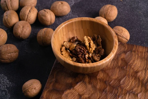 Nueces en cuenco de madera y en la superficie de pizarra azul. Composición saludable de frutos secos y semillas . — Foto de Stock