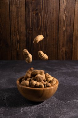 Yer fıstığı rustik dokulu arka plan üzerinde ahşap kase üzerinde süzülen. Sağlıklı gıda ve diyet.