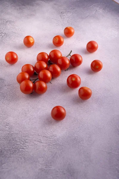 Bunch of cherry tomatoes on white stone concrete table, side view with copy space. Ingredients for cooking. — Stock Photo, Image