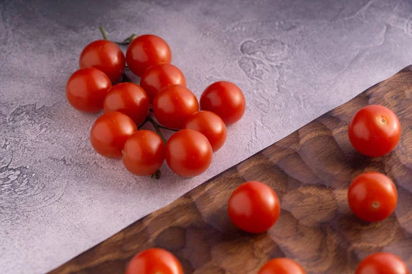 Φρέσκες ντομάτες σε σκαλιστό ξύλινη σανίδα κοπής και φωτεινή υφή επιφάνειας. — Φωτογραφία Αρχείου