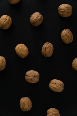 Ceviz siyah yüzey, üst görünümü üzerinde kabuk içinde. Yuvarlak ceviz arka plan. Sağlıklı fındık ve tohum bileşimi.