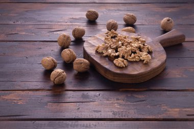 Kesme tahtası ve ahşap masa üzerinde kırık ve bütün ceviz, yan görünüm. Sağlıklı fındık ve tohum bileşimi.