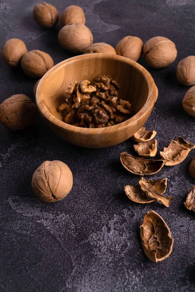 Walnuts in wooden bowl and on black slate surface. Healthy nuts and seeds composition. — Stock Photo, Image