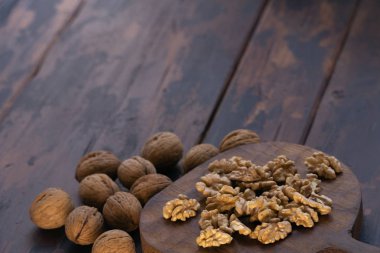 Kesme tahtası ve ahşap masa üzerinde kırık ve bütün ceviz, yan görünüm. Sağlıklı fındık ve tohum bileşimi.