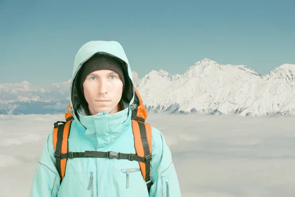 Молодой альпинист зимой смотрит в камеру. Вид спереди. Активный образ жизни в холодную погоду. Зимний горный пейзаж и облачное небо . — стоковое фото