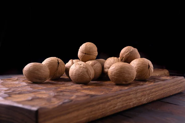 Ramo de nueces enteras sobre tabla de madera tallada. Composición saludable de frutos secos y semillas, fondo . —  Fotos de Stock