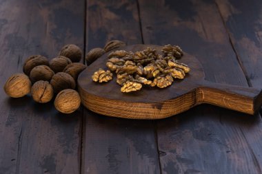 Kesme tahtası ve ahşap masa üzerinde kırık ve bütün ceviz, yan görünüm. Sağlıklı fındık ve tohum bileşimi.