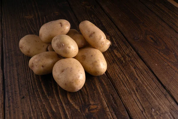 Heap of fresh potatoes on rustic wooden surface. Organic food, carbs, tubers. — Stock Photo, Image