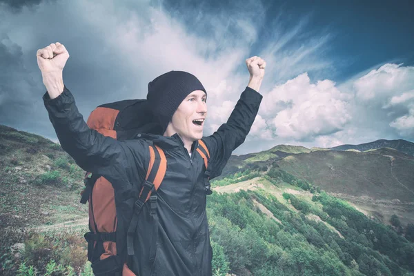 Young hiker shouting out on top with his hands raised, side view. — Stock Photo, Image
