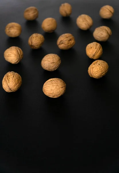 黒い表面、上のビュー上のシェル内のクルミ。丸いクルミの背景。健康的なナッツと種子組成物. — ストック写真