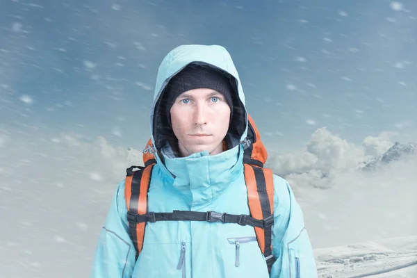 Jovem alpinista do sexo masculino na montanha de inverno vista superior olhando para a câmera. Vista frontal. Estilo de vida ativo em tempo frio. Inverno paisagem de montanha e céu nublado . — Fotografia de Stock