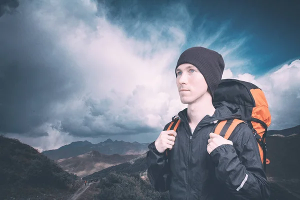 Aktiver junger Mann beim Bergwandern, Seitenblick auf bewölkten Landschaftshintergrund. aktiver Lebensstil und Tourismus. — Stockfoto