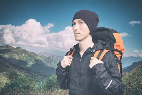 Aktiver junger Mann beim Bergwandern, Seitenblick auf bewölkten Landschaftshintergrund. aktiver Lebensstil und Tourismus. — Stockfoto