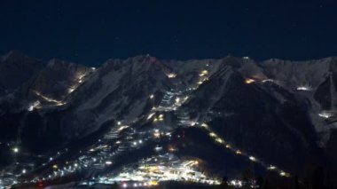 Yıldız dolu gökyüzü altında geceleri kayak parkurları üzerinde çalışan ratraf. Muhteşem gece zaman aşımı.