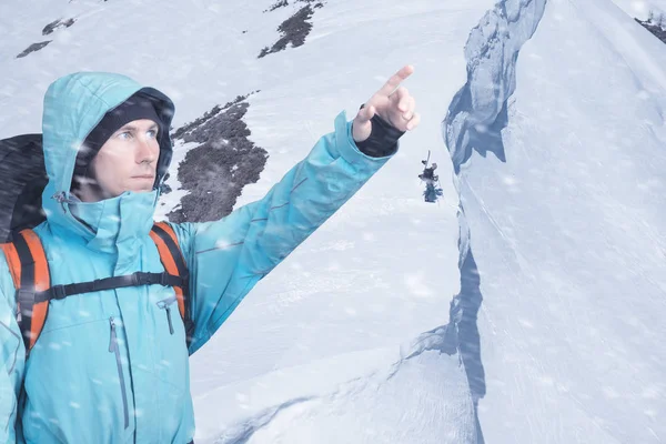 Портрет авантюрного молодого человека на зимнем склоне горы, указывающий . — стоковое фото