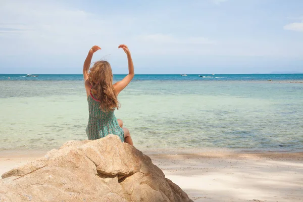 Mädchen in Kleid sitzt auf einem Felsen am Meer — Stockfoto