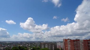 Şehrin üzerinde akan beyaz bulutlar, parlak mavi gökyüzü. Zaman dilimleri.