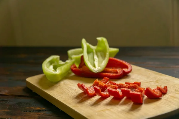 Gesneden rode en groene paprika op een snijplank. Biologisch voedsel en coocking. — Stockfoto