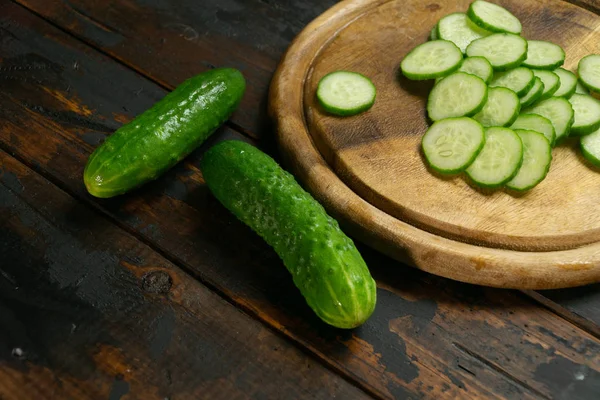 Whole and sliced cucumber on a wooden cutting board. Slices of cucumber. — Stock Photo, Image