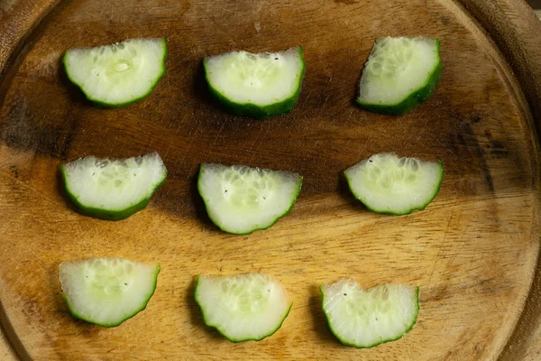 Slices of cucumber on a wooden cutting board. Top view. — Stock Photo, Image