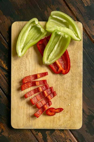 Gesneden rode en groene paprika op een snijplank. Biologisch voedsel en coocking. — Stockfoto