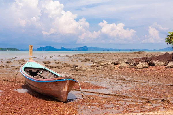 Traditionell longtailbåt på sandstranden vid lågvatten. Havsutsikt med öar på horisonten och moln i skyen. — Stockfoto
