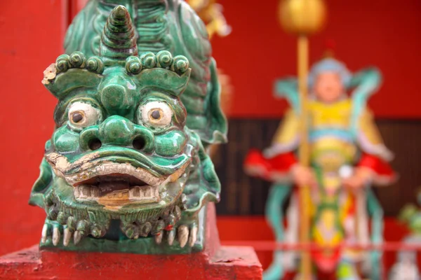 Zbliżenie tradycyjnej sztuki chińskiej rzeźby głowy zwierząt z rozmyte tło chińskiej świątyni. Zielona głowa smoka na żywe tło. — Zdjęcie stockowe