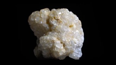 Beyaz kristal mineralin makro çekimi, rotasyonla yakın çekim. Siyah arka da izole.