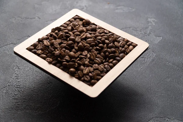 Grains de café dans une boîte en bois sur un fond sombre. — Photo