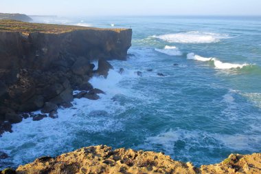Bir balıkçı Amoreira beach (Aljezur), Costa Vicentina, Algarve, Portekiz yakınındaki yüksek kayalıklarla yukarıda olta balıkçılığı