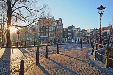 Çarpık ve renkli miras binalar Herengracht kanalı ve yanındaki Brouwersgracht Canal, Amsterdam, Hollanda. Bir güneş yıldız sunrise çekilen resmi.