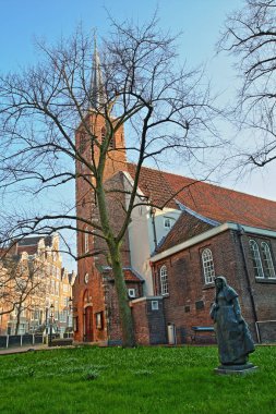 Amsterdam, Hollanda-05 Nisan 2019: Begijnhof, Amsterdam 'ın en eski hofjes biri iç avlu, ön planda bir beguine heykeli ile