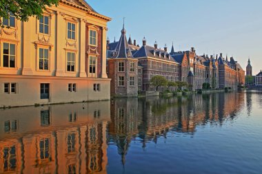 Mauritshuis ve Binnenhof yansımaları (13 yüzyıl gotik kale) gün batımında Hofvijver gölü üzerinde, sağda Sint Jacobskerk Grote saat kulesi ile, Lahey, Hollanda