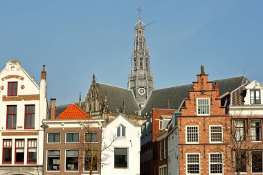 Arka planda St Bavokerk Kilisesi saat kulesi ile Spaarne nehri boyunca bulunan geleneksel ve renkli cepheler, Haarlem, Hollanda