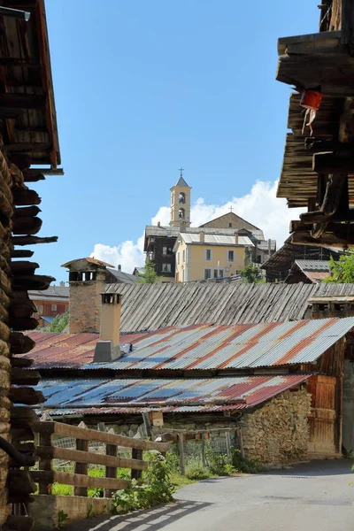 Traditional wooden balconies and roofs with the church in the background in Saint Veran village, Queyras Regional Natural Park, Southern Alps, France