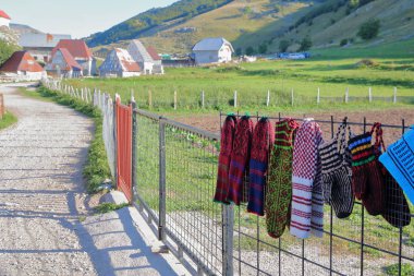 Ön planda yün çoraplar ve eldivenlerle (turistler için satışta) Lukomir köyü. Lukomir, 1469 metreyle Bosna 'nın en yüksek ve tüm ülkenin en ücra köyü olan Bosna-Hersek' te yer alıyor.