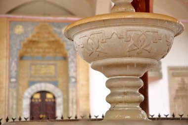Gazi Husrev Begova Camii 'nin avlusunda yer alan çeşmenin (Sadrvan) yakınında, arka planda Saraybosna, Bosna-Hersek' teki namaz odasının süslü girişi yer alıyor.