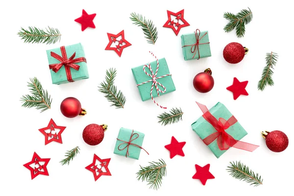 Kış desen beyaz arka plan üzerinde Noel süsler (küçük Noel hediyeleri, kırmızı Noel topları, yeşil Çamın dalları ve kırmızı yıldız) ile.