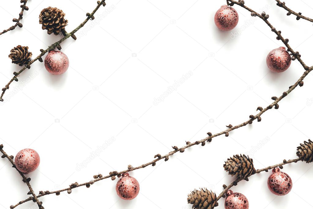 Dry larch branches with cones and pink christmas balls on white background. Copy space.