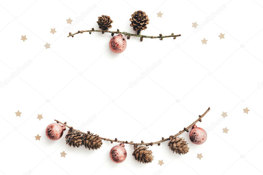 Dry larch branches with cones and pink christmas balls on white background. Copy space.