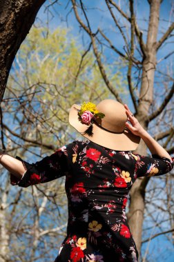 Kadın kulübesini tutuyor ve dışarıdaki parkta gökyüzüne bakıyor.