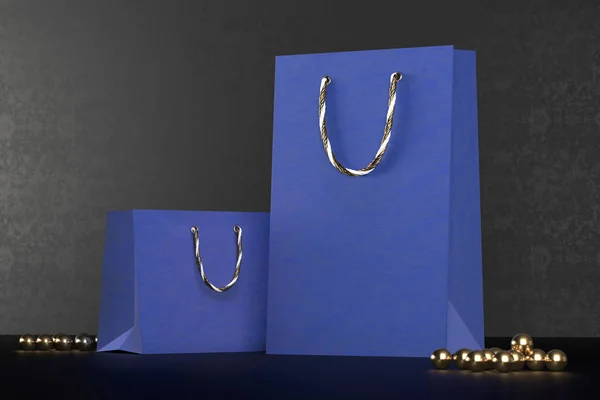 Prima azul bolsas de compras maqueta, paquete para compras en un fondo negro. Bolsa de compras de papel azul con asas doradas se burlan. Bolsas de papel de lujo, 3d renderizado . — Foto de Stock