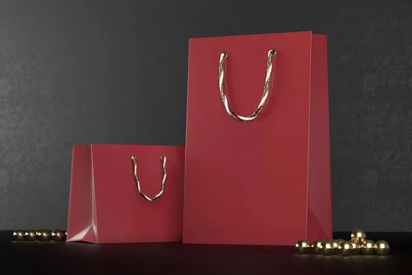 Bolsas redshopping premium maqueta, paquete para compras en un fondo negro. Bolsa de compras de papel rojo con asas doradas se burlan. Bolsas de papel de lujo, 3d renderizado . —  Fotos de Stock